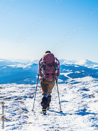 Backpacker mountain hiker woman on a snowy mountain ridge from the back