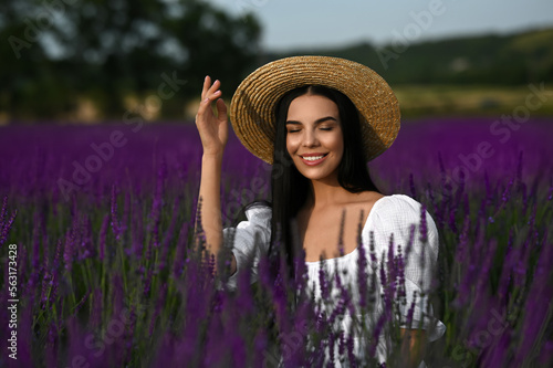 Beautiful young woman with straw hat in lavender field