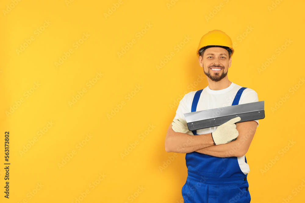Professional worker with putty knife in hard hat on orange background, space for text Professional worker with putty knife in hard hat on orange background, space for text