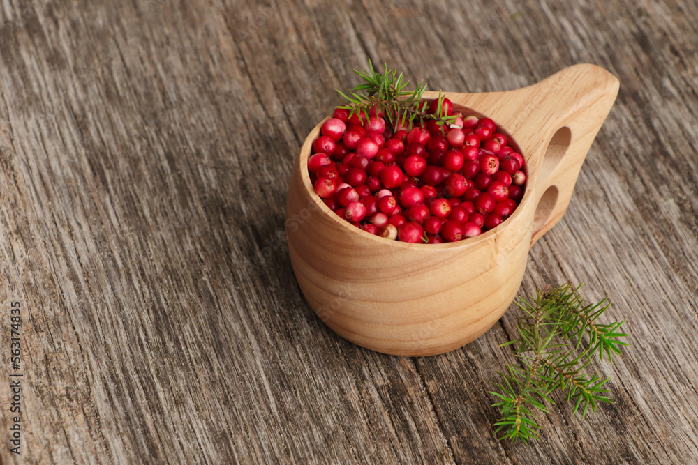 Cup with tasty ripe lingonberries and spruce twigs on wooden surface, space for text Cup with tasty ripe lingonberries and spruce twigs on wooden surface, space for text