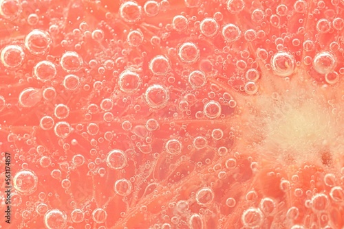 Slice of grapefruit in sparkling water. Grapefruit slice covered by bubbles in carbonated water. Grapefruit slice in water with bubbles