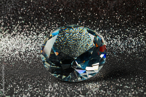 Beautiful dazzling diamond on shiny glitter background, closeup. Precious gemstone photo