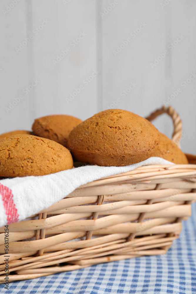 Wicker basket with tasty oatmeal cookies on checkered cloth, closeup