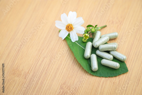 Fototapeta Naklejka Na Ścianę i Meble -  Herbal medicine in capsules from herb leaf on rustic wooden table with copy space for medical background. healthy eating with natural product for good living.
