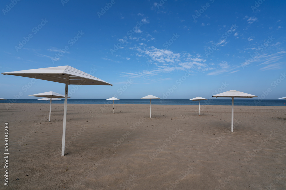 A deserted beach with wooden umbrellas on the shore of the Baltic Sea in the village of Yantarny, Kaliningrad region, Russia