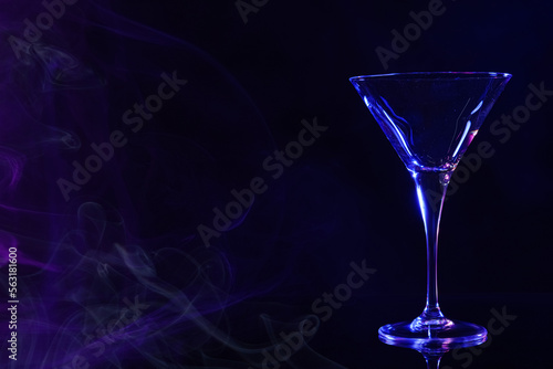Empty clean martini glass on mirror table in neon lights, space for text