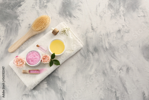 Flat lay composition with pink sea salt, flowers and different spa products on textured table. Space for text