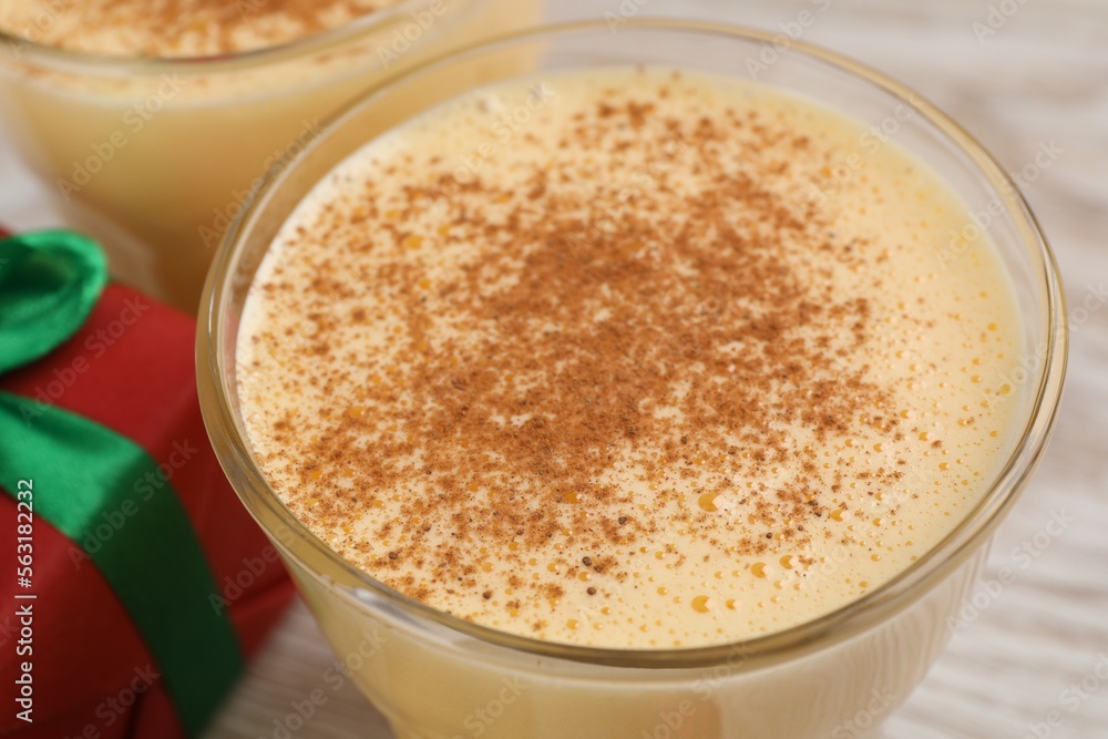 Tasty eggnog with cinnamon on white wooden table, closeup Tasty eggnog with cinnamon on white wooden table, closeup