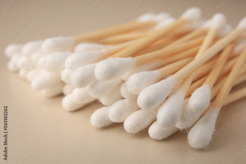 Many clean cotton buds on beige background, closeup Many clean cotton buds on beige background, closeup