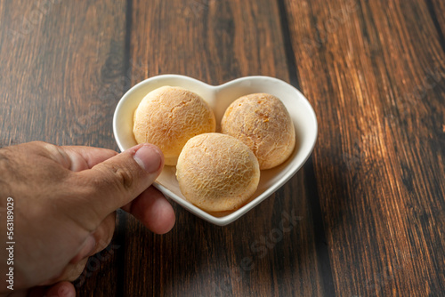 Wallpaper Mural male hand serving cheese bread in heart-shaped container on wooden table Torontodigital.ca