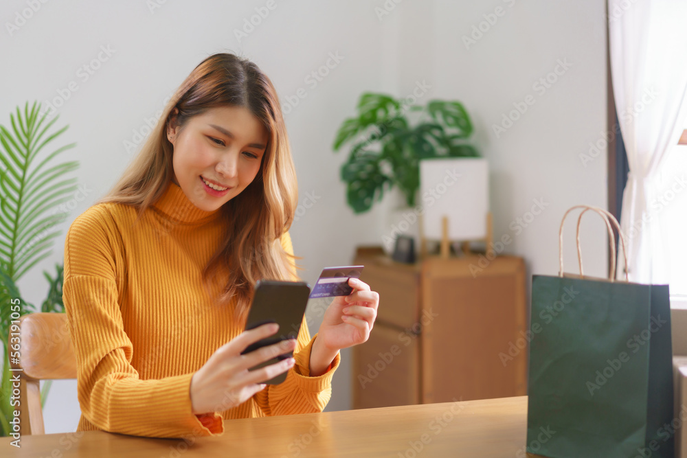 Work from home concept, Asian woman is typing credit card data on smartphone to shopping online Work from home concept, Asian woman is typing credit card data on smartphone to shopping online