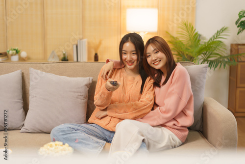 Friendship concept, LGBT lesbian couple switching channel while embrace together to watching movie
