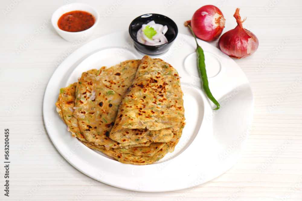 Indian traditional Hot Onion Paratha with tomato chutney. Indian onion stuffed Flatbread. also known as Pyaz ke parathe in Hindi. over a light background with copy space. Indian traditional Hot Onion Paratha with tomato chutney. Indian onion stuffed Flatbread. also known as Pyaz ke parathe in Hindi. over a light background with copy space.
