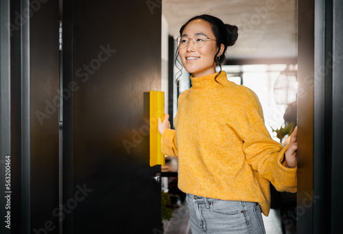 Foto Thinking, smile and Asian woman opening a door to an office at a graphic design startup company