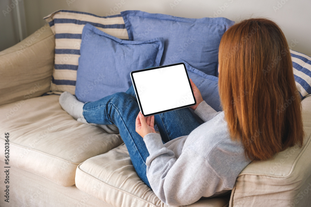 Mockup image of a woman holding digital tablet with blank desktop screen while lying on a sofa at home Mockup image of a woman holding digital tablet with blank desktop screen while lying on a sofa at home