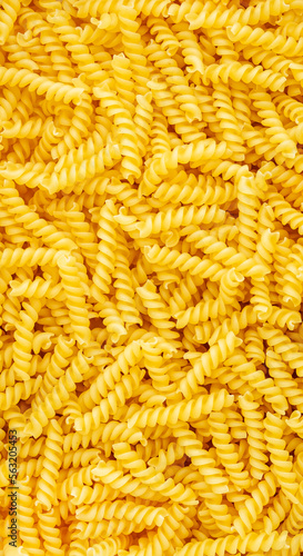 Raw dry fusilli pasta, food background texture, top view vertical banner