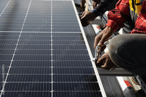 Smiling male technician in blue suit installing solar blue solar modules with screws, male electric panel, renewable energy, sustainable energy, innovative renewable energy panels