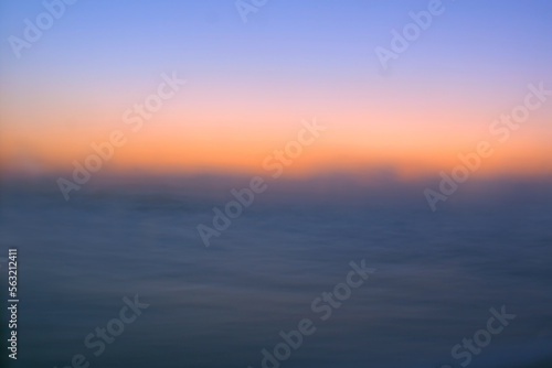 Sunrise horizon over the dark ocean where the sun begins to brighten the sky, retouched and color manipulated image illustration.