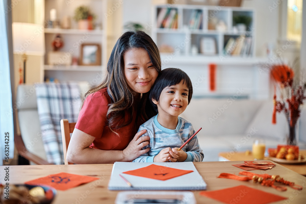 Fototapeta premium Happy Asian boy and his mother making traditional Fai Chun for Chinese New Year at home.