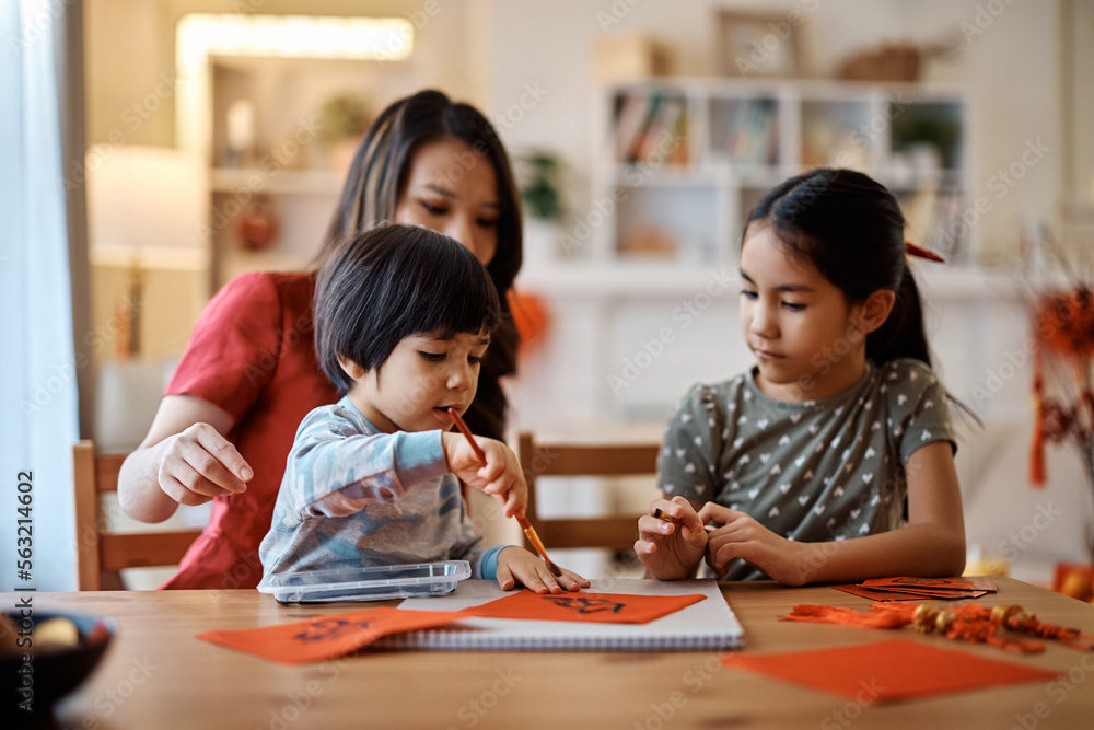Chinese kids learning to write Fai Chun with their mother while decorating home for Lunar New Year. Chinese kids learning to write Fai Chun with their mother while decorating home for Lunar New Year.