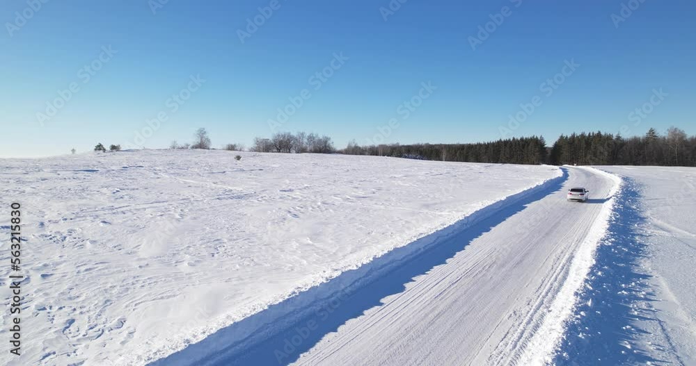 The car passed a road sign that warns the driver that he is approaching a section of the road where wildlife can enter the roadway. Deer images on a road sign. Country road in winter, aerial view. The car passed a road sign that warns the driver that he is approaching a section of the road where wildlife can enter the roadway. Deer images on a road sign. Country road in winter, aerial view.
