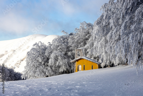 PIccola chiesa gialla in mezzo alla neve fresca sul Monte Nerone, Marche.