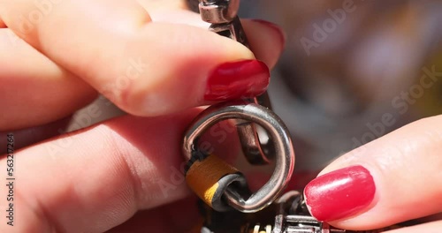 The video shows female finger releasing a snap-hook fastened to the black bag