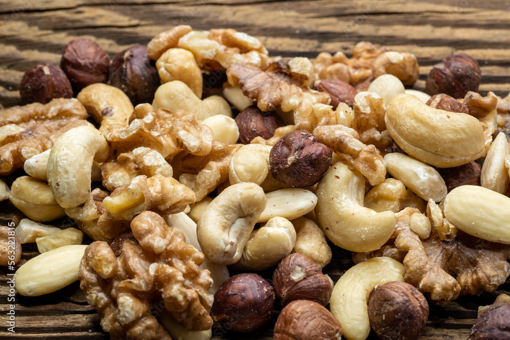 Mix of tasty nuts on a wooden surface. Cashews, almonds, hazelnuts and walnuts on a brown table. Mix of tasty nuts on a wooden surface. Cashews, almonds, hazelnuts and walnuts on a brown table.