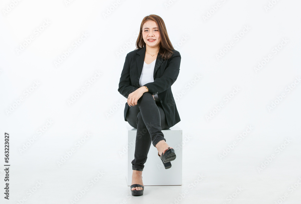 Portrait isolated cutout studio full body shot of Asian confident female professional successful businesswoman in formal black suit high heels sitting on square box look at camera on white background Portrait isolated cutout studio full body shot of Asian confident female professional successful businesswoman in formal black suit high heels sitting on square box look at camera on white background