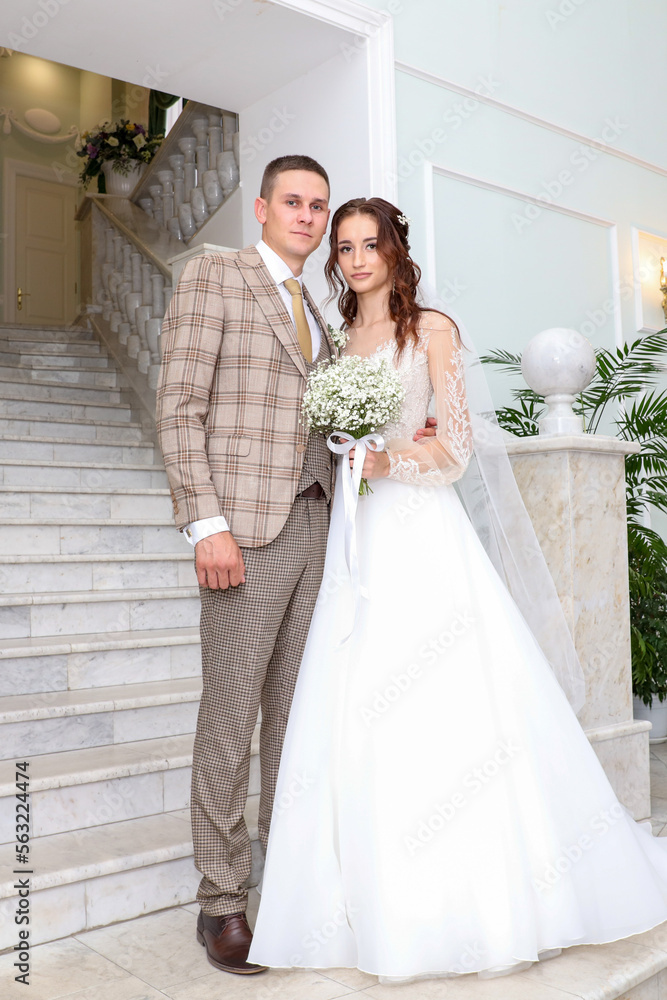 The bride and groom in a wedding dress on the stairs.