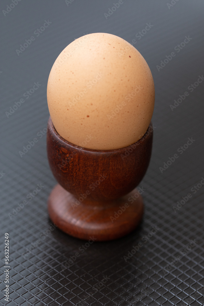 a boiled egg placed in a wooden brown support a boiled egg placed in a wooden brown support