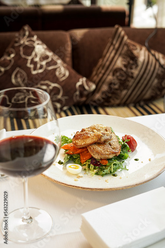 salad with chicken in a plate on the table with a glass of wine vertical photo 