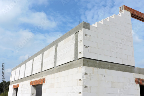 A reinforced concrete beam and reinforced concrete columns, reinforced brick lintels, a rough door and windows openings, a gable wall, walls made of aac blocks, blue sky in the background photo