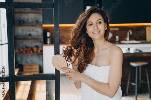 Fotografia Young hispanic woman combs her long curly hair