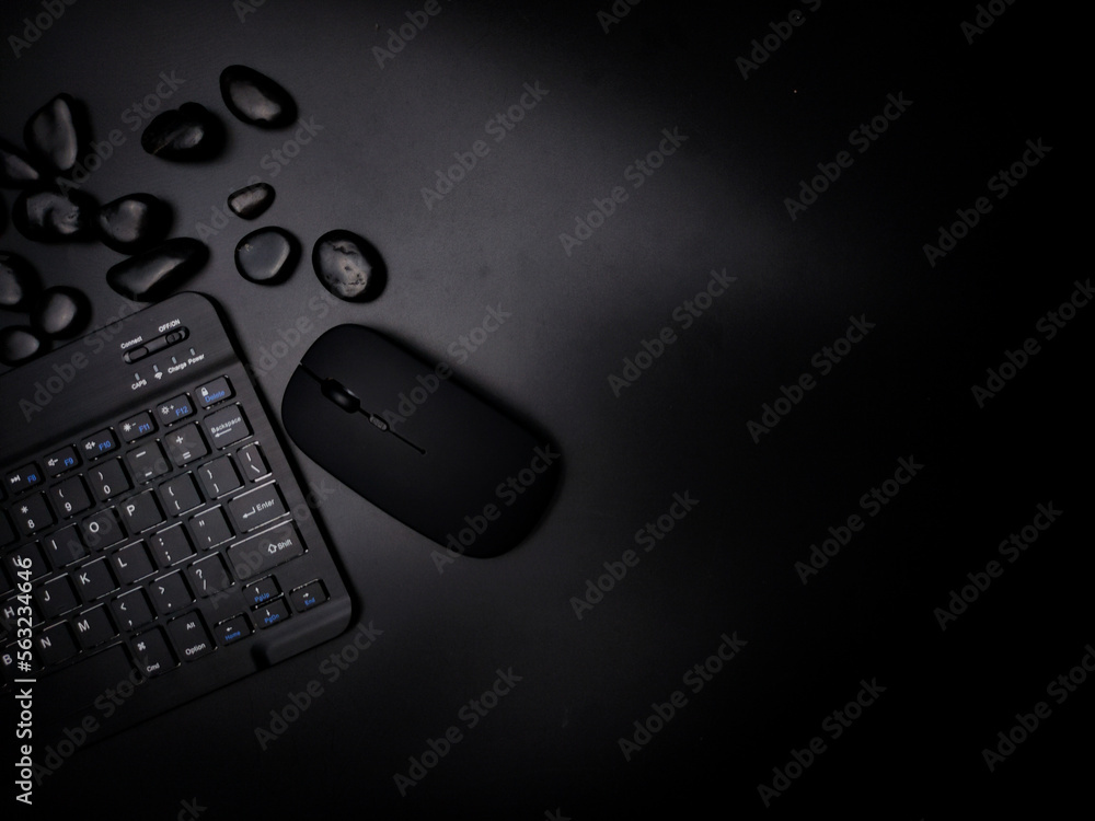 A black wireless keyboard and mouse with black stone on a black background. A black wireless keyboard and mouse with black stone on a black background.