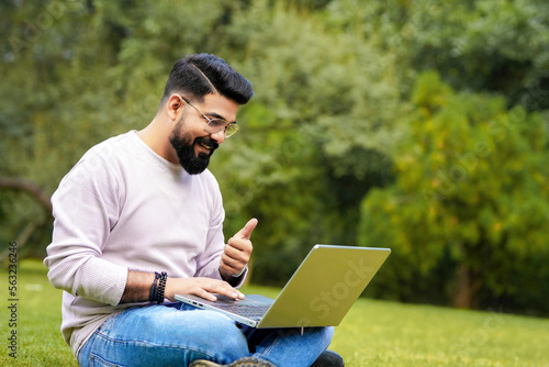 young indian man using laptop and giving expression like talking on video call.