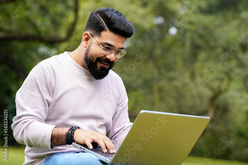 young indian man using laptop and giving expression like talking on video call. © Niks Ads