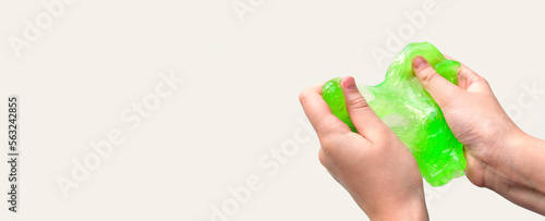 Hand Playing with textured slime on white background. Teen hand holding green shining slime with bubbles, stretching gooey substance. Teenage Girl squeezing slime toy to the sides. Liquid toy. Handgum