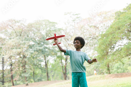 Smiling African American boy playing with toy airplane outdoor. Kid having fun with toy airplane in the park. Happy black people. Education and field trips concept