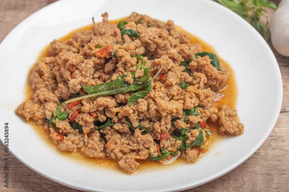 Pad kaprao, minced chicken in white plate on wooden background Pad kaprao, minced chicken in white plate on wooden background