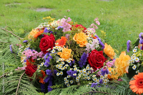 Bunte Blumen der Trauer schmücken ein Grab auf dem Friedhof photo