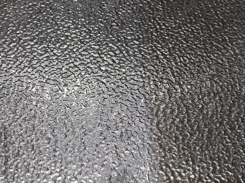 Repeating pattern on metal. Metal texture. Blurry reflections of light on a curved metal sheet. Abstract texture.
