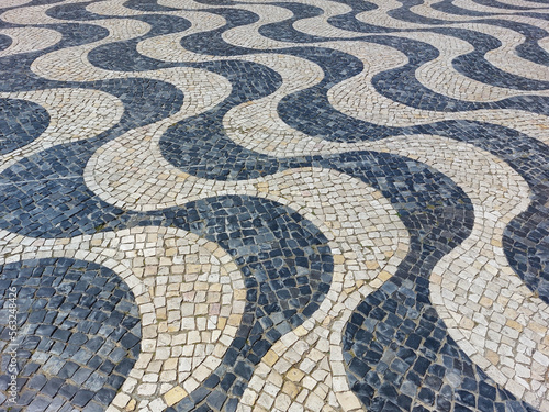 A beautiful pattern on a street tile paved with square marble stones in two shades - light and dark