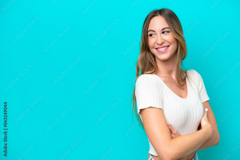 Young caucasian woman isolated on blue background with arms crossed and happy Young caucasian woman isolated on blue background with arms crossed and happy