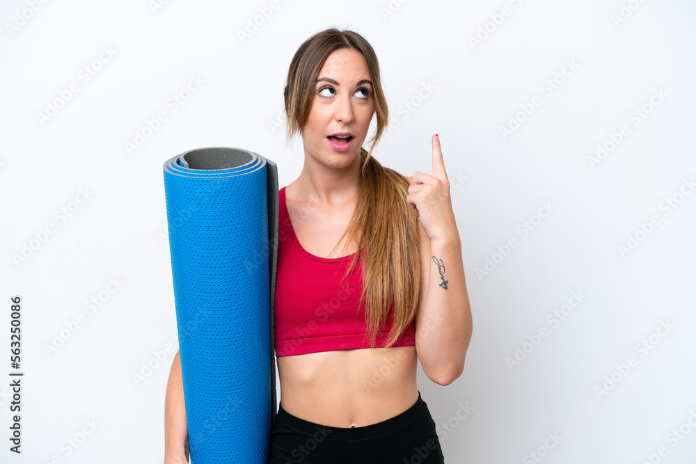 Young sport woman going to yoga classes while holding a mat isolated on white background thinking an idea pointing the finger up Young sport woman going to yoga classes while holding a mat isolated on white background thinking an idea pointing the finger up