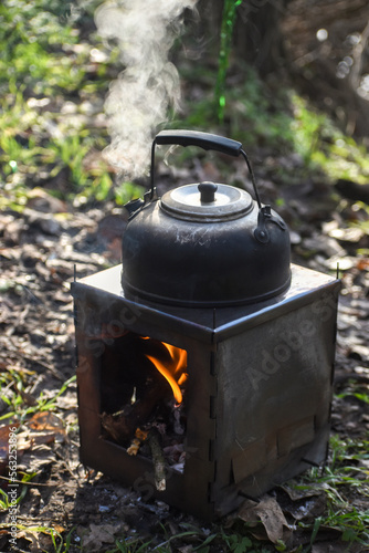 Kettle boils on tourist wood burning stove, camp kitchen