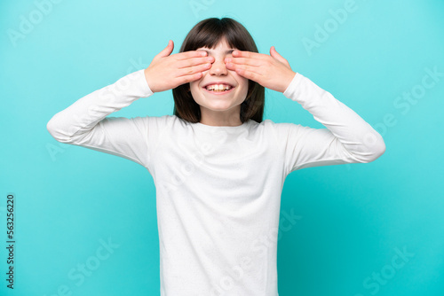 Little caucasian girl isolated on blue background covering eyes by hands and smiling © luismolinero