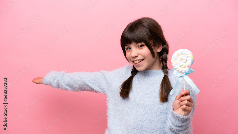 Little caucasian girl holding a lollipop extending hands to the side for inviting to come Little caucasian girl holding a lollipop extending hands to the side for inviting to come