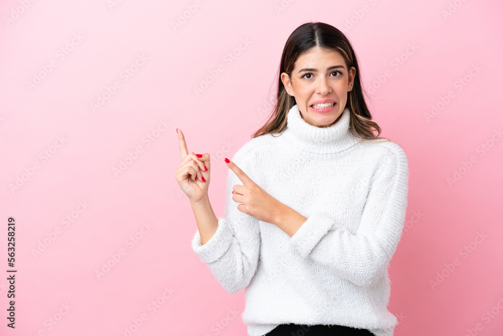 Young Italian woman isolated on pink background frightened and pointing to the side Young Italian woman isolated on pink background frightened and pointing to the side