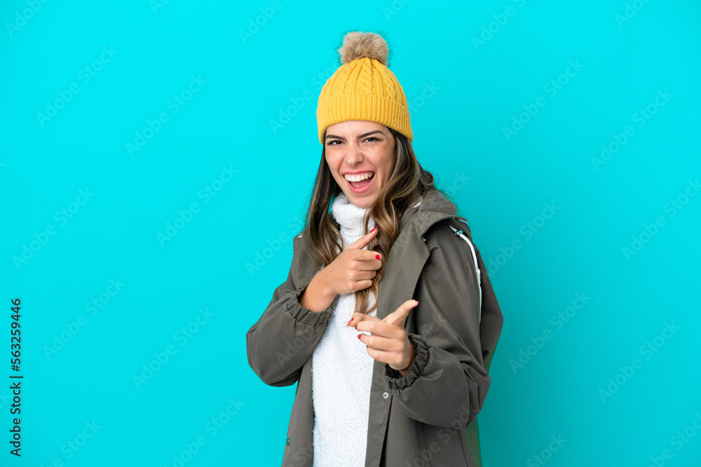 Young Italian woman wearing winter jacket and hat isolated on blue background pointing to the front and smiling Young Italian woman wearing winter jacket and hat isolated on blue background pointing to the front and smiling